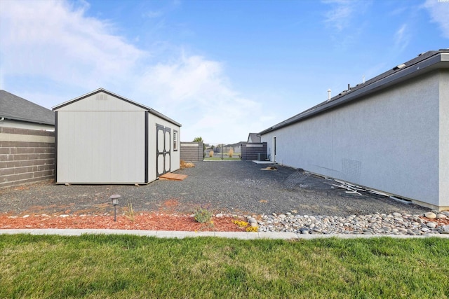 view of yard with a storage shed, fence, and an outbuilding