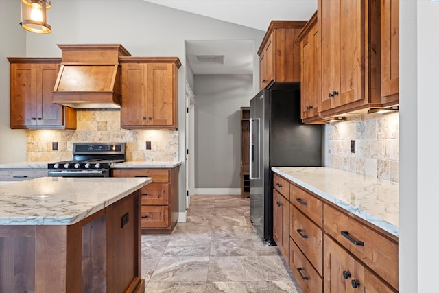 kitchen with stainless steel appliances, custom exhaust hood, visible vents, and brown cabinets