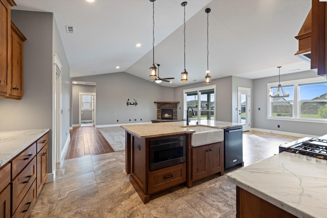 kitchen with dishwasher, stainless steel microwave, open floor plan, a kitchen island with sink, and pendant lighting