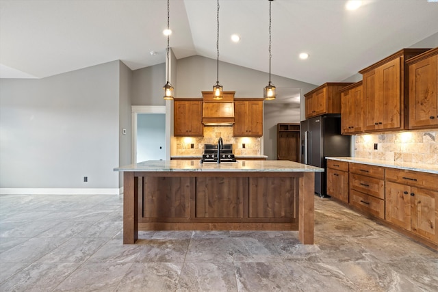 kitchen with a center island with sink, light stone counters, decorative light fixtures, custom exhaust hood, and high end black fridge