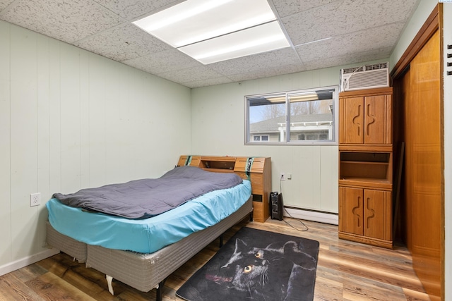 405 W 7th Ave, Ritzville, WA 99169 - bedroom with hardwood / wood-style flooring, a baseboard radiator, a wall mounted AC, and a drop ceiling