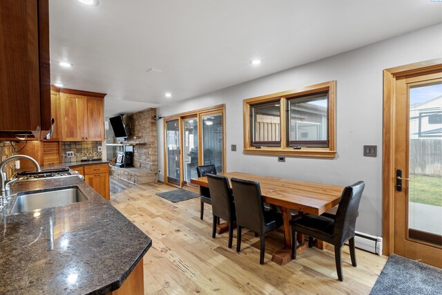 405 W 7th Ave, Ritzville, WA 99169 - kitchen with sink, a fireplace, light hardwood / wood-style floors, decorative backsplash, and a baseboard heating unit