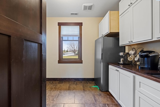 kitchen featuring white cabinetry and stainless steel fridge