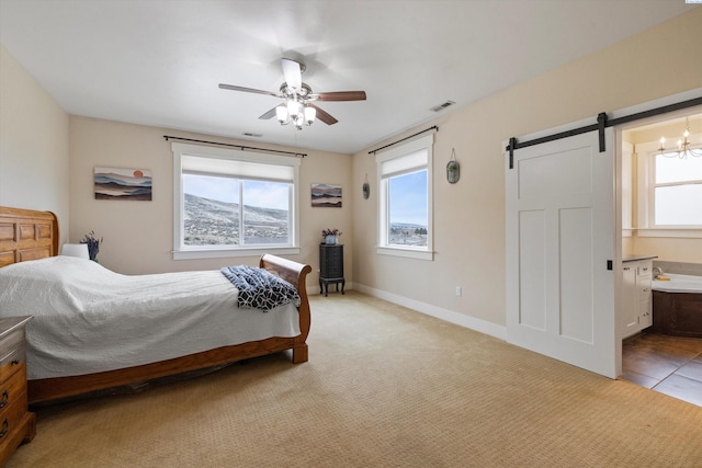 carpeted bedroom with ceiling fan, ensuite bath, and a barn door