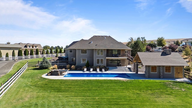 rear view of house featuring an outbuilding, a lawn, pool water feature, and a patio area