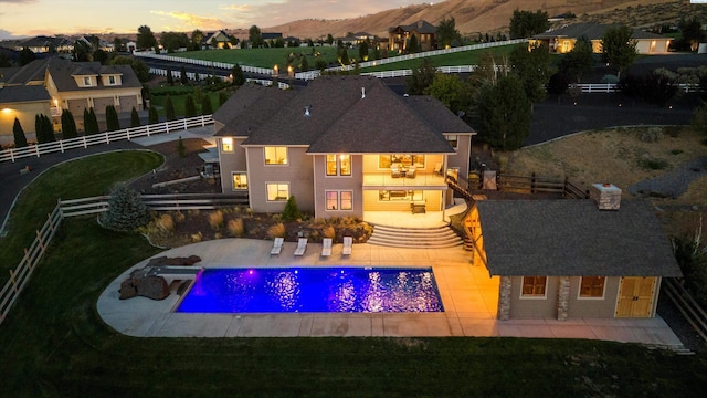 pool at dusk with a patio area