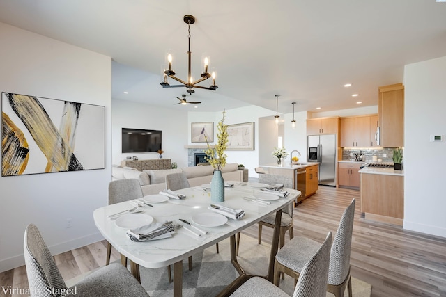 1060 SW Panorama Dr, Pullman, WA 99163 - dining room featuring light wood finished floors, a stone fireplace, ceiling fan with notable chandelier, recessed lighting, and baseboards