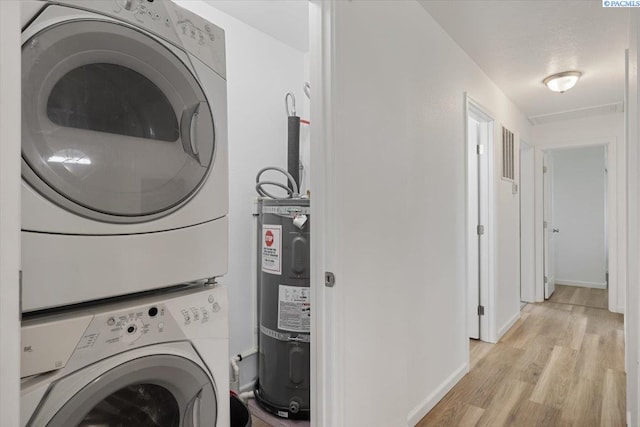 3925 W Okanogan Ave, Kennewick, WA 99336 - laundry area featuring stacked washer and clothes dryer, secured water heater, light wood finished floors, and baseboards