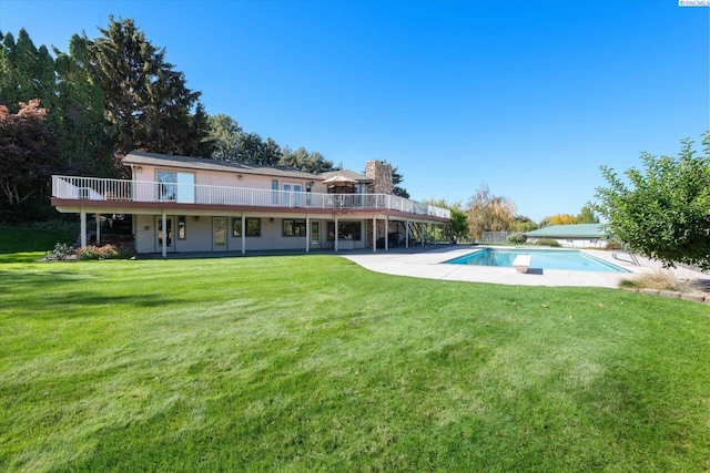 back of property with an outdoor pool, a deck, a patio, and a yard