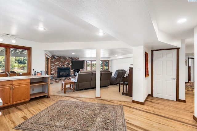 living area with baseboards, plenty of natural light, a fireplace, and light wood-style floors