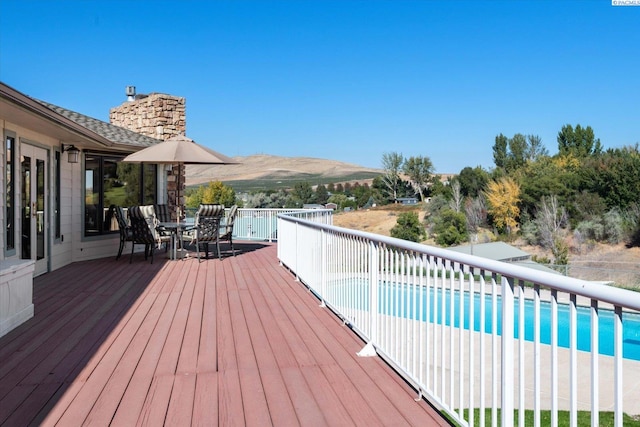 deck with a fenced in pool, outdoor dining space, and a mountain view