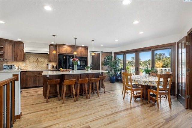 dining area featuring light wood-type flooring, a barn door, recessed lighting, and french doors