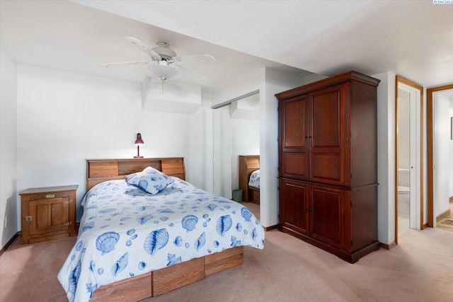 bedroom with ceiling fan, light carpet, baseboards, a closet, and ensuite bath