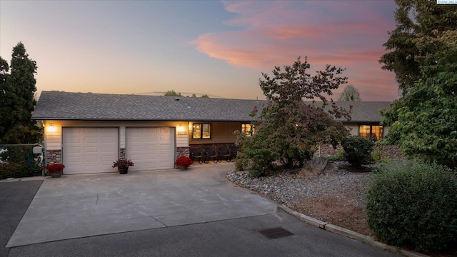 view of front of property featuring a garage, stone siding, roof with shingles, and concrete driveway