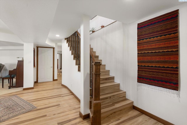 stairway featuring baseboards, wood finished floors, and recessed lighting