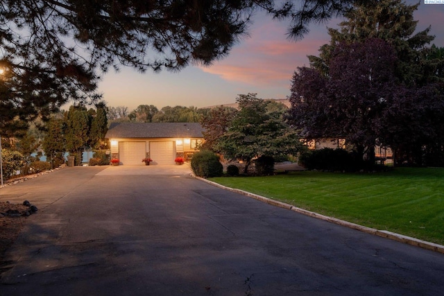 view of front facade with driveway, an attached garage, and a front lawn