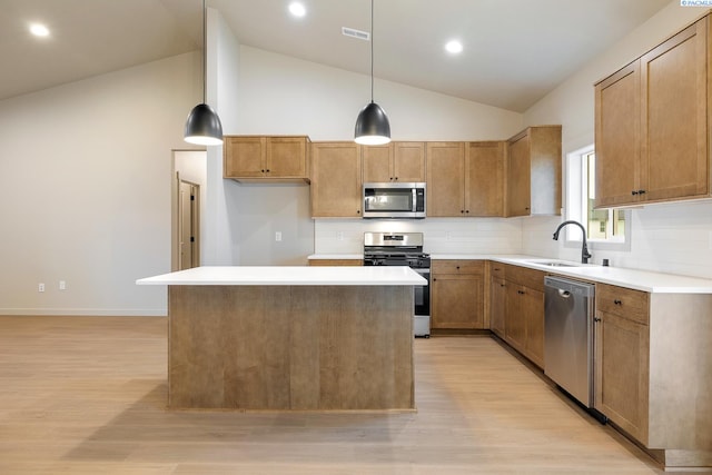 kitchen with stainless steel appliances, hanging light fixtures, a center island, and light hardwood / wood-style flooring