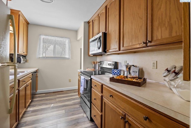 213 Bernard Ave, Richland, WA 99352 - kitchen with appliances with stainless steel finishes, light countertops, light wood finished floors, and brown cabinetry