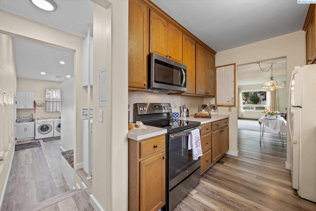 213 Bernard Ave, Richland, WA 99352 - kitchen with stainless steel appliances, washer and clothes dryer, light wood-style floors, light countertops, and brown cabinets