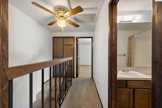 hall featuring a sink, light colored carpet, and an upstairs landing