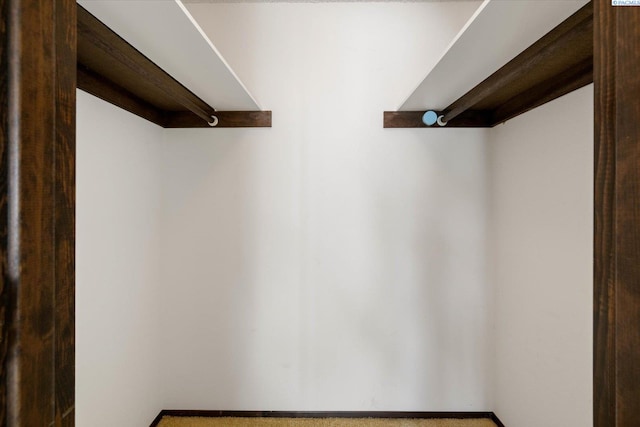 walk in closet featuring beam ceiling
