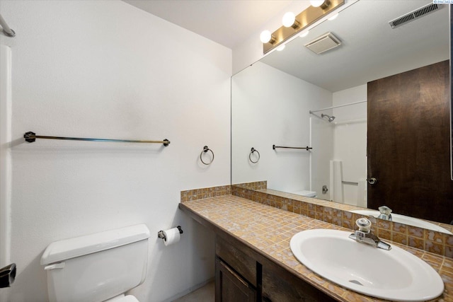 full bath with toilet, a shower, vanity, and tasteful backsplash
