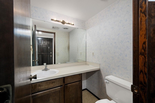 half bathroom with wallpapered walls, toilet, and vanity