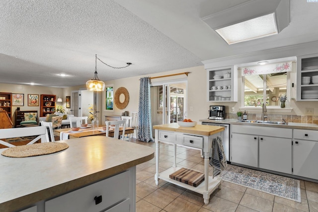 912 Rd 44, Pasco, WA 99301 - kitchen with stainless steel dishwasher, open shelves, open floor plan, light tile patterned floors, and a textured ceiling