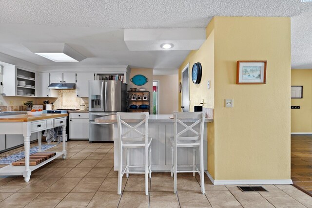 912 Rd 44, Pasco, WA 99301 - kitchen featuring stainless steel fridge, under cabinet range hood, a textured ceiling, range, and a peninsula