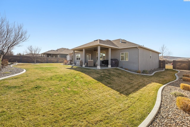 rear view of property with a patio, a fenced backyard, a ceiling fan, a lawn, and stucco siding