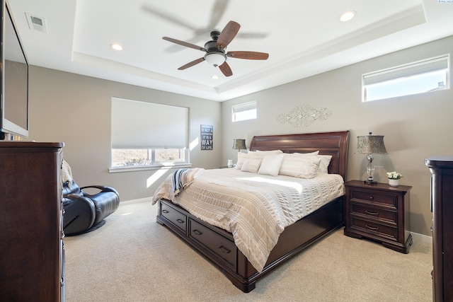 bedroom with light carpet, recessed lighting, a raised ceiling, and baseboards