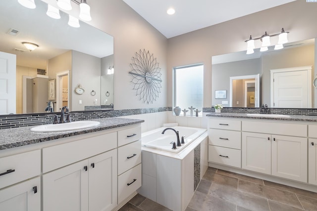 bathroom featuring two vanities, visible vents, a sink, and a bath