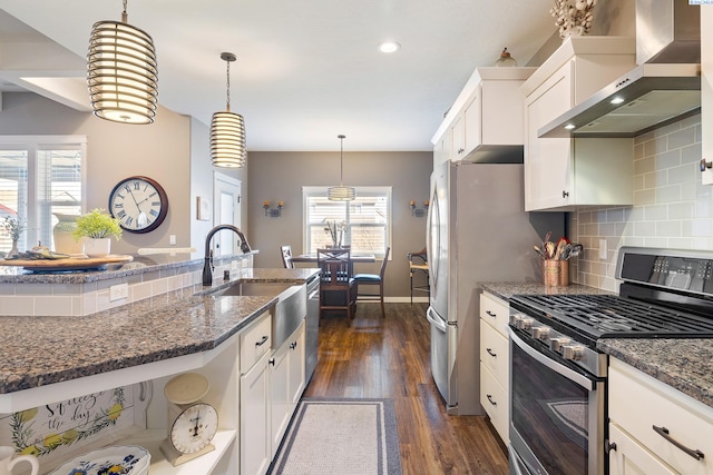 kitchen featuring stainless steel appliances, a sink, white cabinetry, wall chimney range hood, and dark wood-style floors