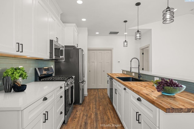 kitchen with sink, butcher block countertops, white cabinetry, hanging light fixtures, and stainless steel appliances