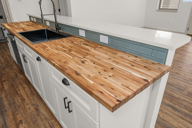 kitchen with white cabinetry, a center island, sink, and wooden counters