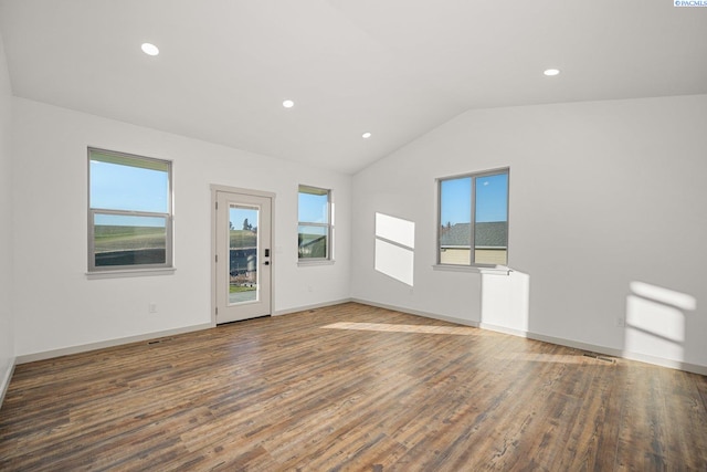 unfurnished room with vaulted ceiling, a wealth of natural light, and dark hardwood / wood-style flooring