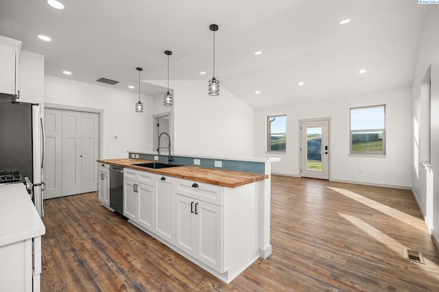 kitchen featuring pendant lighting, white cabinetry, sink, wooden counters, and a kitchen island with sink