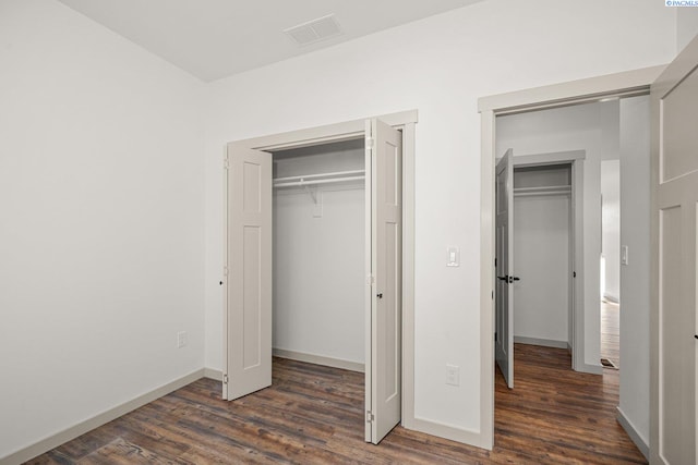 unfurnished bedroom featuring multiple closets and dark hardwood / wood-style floors