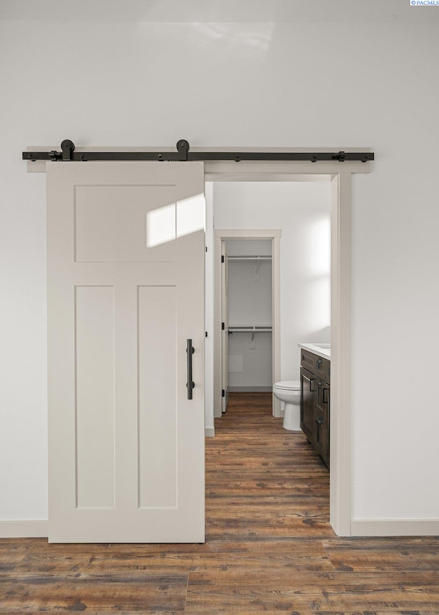 hallway with a barn door and dark hardwood / wood-style floors