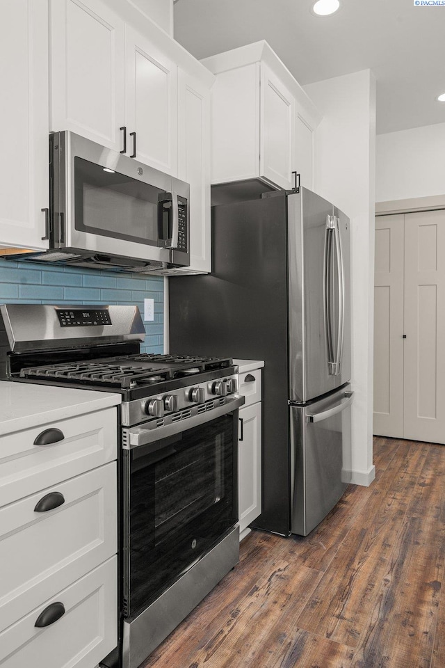 kitchen with stainless steel appliances, dark hardwood / wood-style flooring, white cabinets, and backsplash