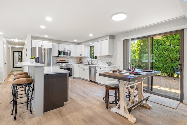 1830 W 23rd Ave, Kennewick, WA 99337 - kitchen featuring appliances with stainless steel finishes, tasteful backsplash, a breakfast bar, light wood-type flooring, and light countertops