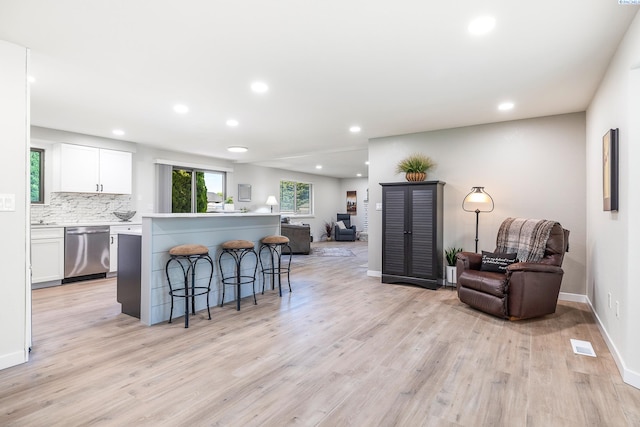 1830 W 23rd Ave, Kennewick, WA 99337 - kitchen with dishwasher, open floor plan, a breakfast bar, light wood-type flooring, and white cabinets