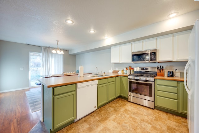 kitchen featuring appliances with stainless steel finishes, decorative light fixtures, sink, white cabinets, and green cabinetry