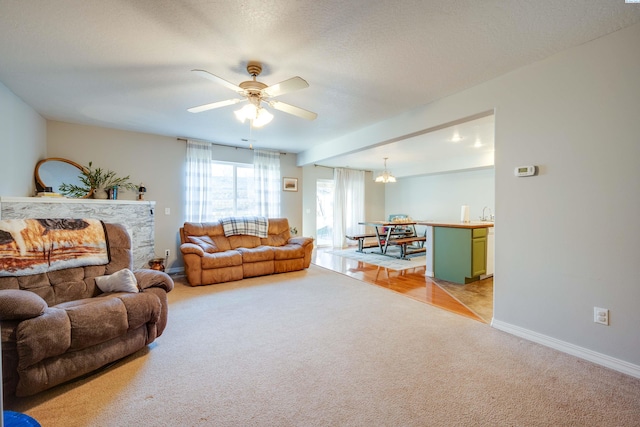 carpeted living room featuring ceiling fan with notable chandelier and a textured ceiling