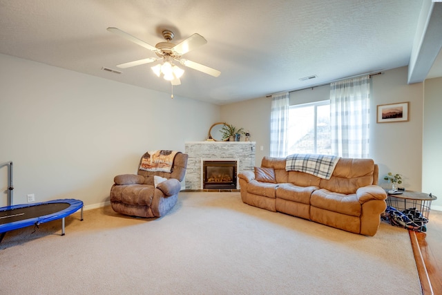 carpeted living room with ceiling fan, a fireplace, and a textured ceiling