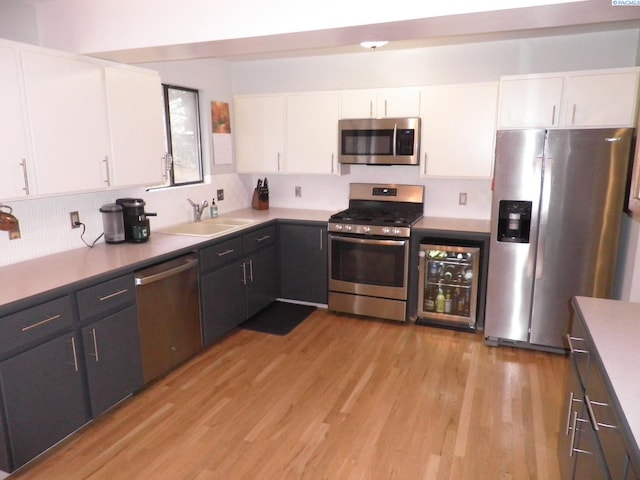 kitchen with white cabinetry, sink, beverage cooler, stainless steel appliances, and light wood-type flooring