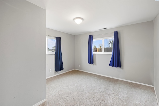 unfurnished room with carpet, visible vents, and baseboards