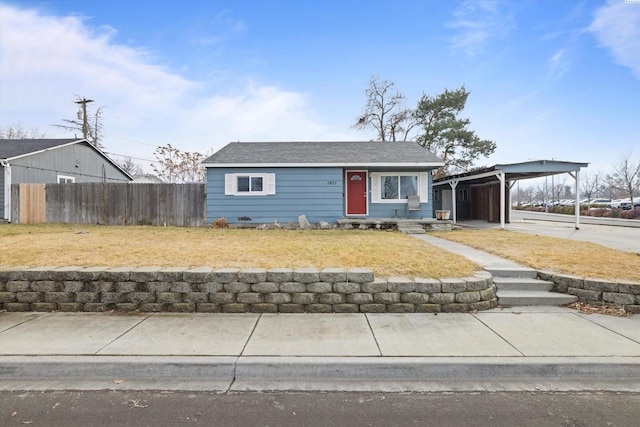 view of front of property featuring a carport, a front lawn, concrete driveway, and fence