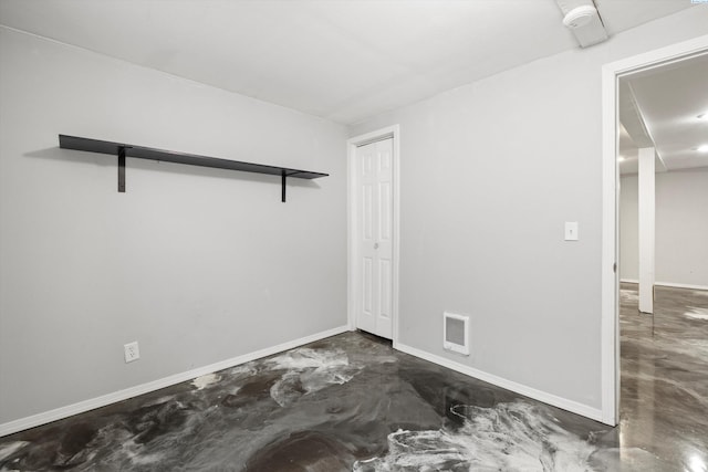 empty room featuring concrete flooring, visible vents, and baseboards