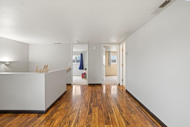 empty room with baseboards, visible vents, and wood finished floors